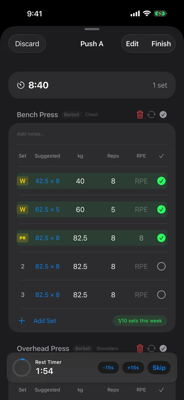 Active Push A workout in PRGRS: bench press with two warm-up sets marked W, a Suggested column showing 82.5 × 8, a first working set of 82.5 kg × 8 at RPE 8 marked PR, a 1/10 sets this week chip, and a rest timer with −15s, +15s and Skip